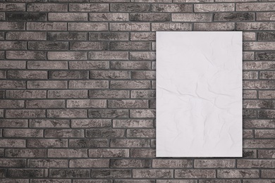 Blank creased poster on grey brick wall. Mockup for design 