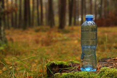 Photo of Plastic bottle of fresh water in forest, space for text