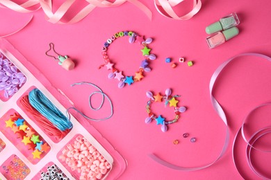 Photo of Handmade jewelry kit for kids. Colorful beads, ribbons and bracelets on bright pink background, flat lay