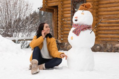 Young woman near funny snowman outdoors. Winter vacation