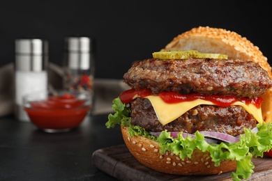 Delicious burger with meat cutlets on black table, closeup. Space for text