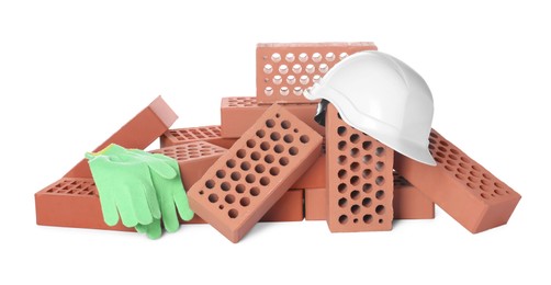 Pile of red bricks, hard hat and gloves on white background