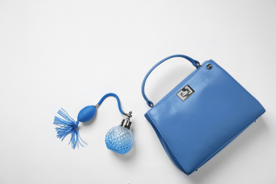 Stylish purse and perfume bottle on white background, top view. Classic blue - color of the Year 2020