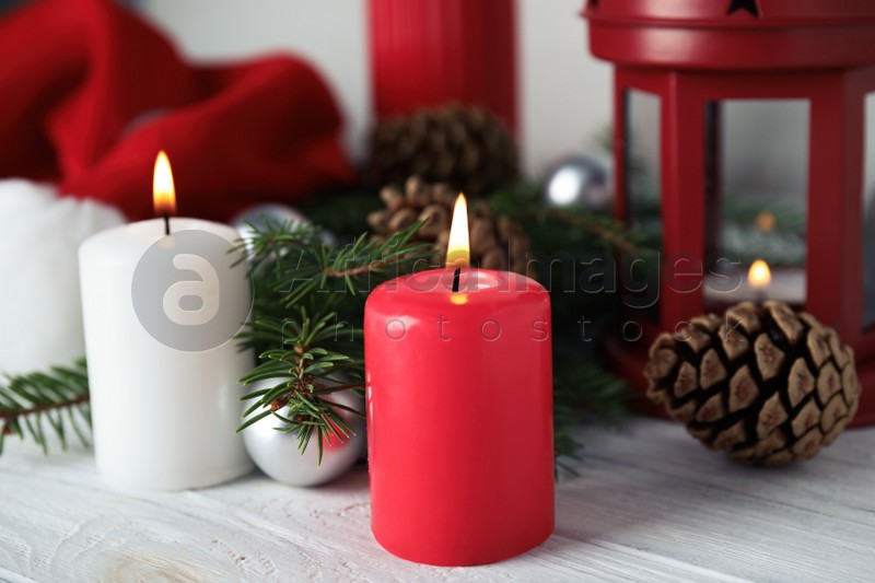 Photo of Burning candles and festive decor on white wooden table. Christmas eve