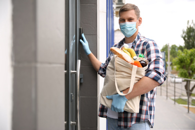 Male volunteer with products ringing doorbell outdoors. Aid during coronavirus quarantine