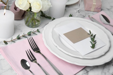 Elegant festive table setting with blank card on white marble background
