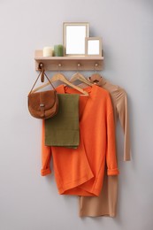 Wooden shelf, fashionable clothes and decorative elements on beige wall indoors. Interior design