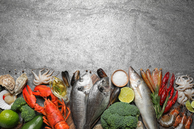 Fresh fish and different seafood on grey table, flat lay. Space for text