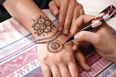 Master making henna tattoo on hand, closeup. Traditional mehndi