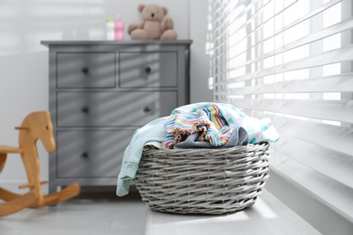 Wicker laundry basket with different clothes on window sill indoors