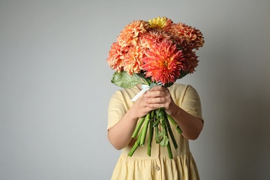 Woman with bouquet of beautiful dahlia flowers on grey background