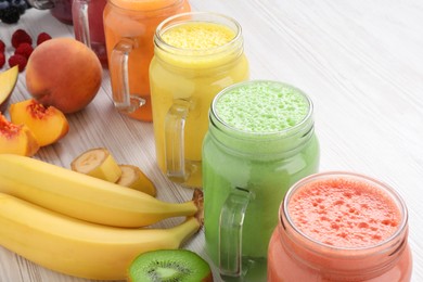 Many different tasty smoothies and ingredients on white wooden table, closeup