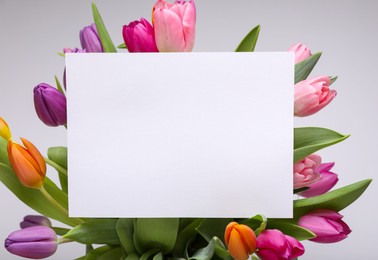 Photo of Blank birthday card on beautiful tulip flowers against grey background, flat lay. Space for text