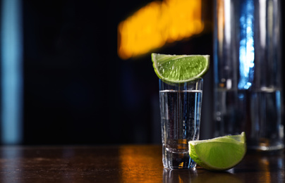 Mexican Tequila shot with lime slices on wooden bar counter. Space for text