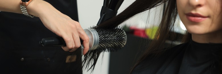 Hairdresser drying woman's hair in beauty salon. Banner design