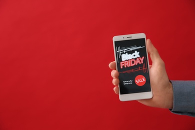 Man shopping online using smartphone on red background, space for text. Black Friday Sale