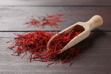 Dried saffron and scoop on wooden table
