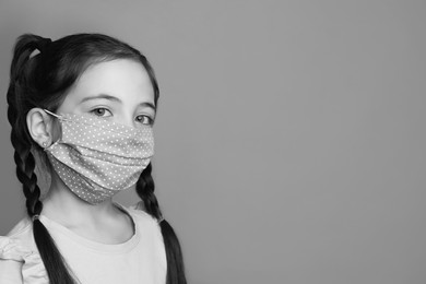 Girl wearing medical face mask on light background, space for text. Black and white photography