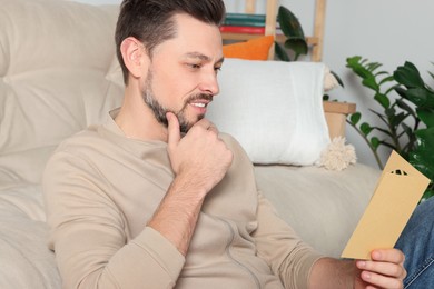 Photo of Man reading greeting card on sofa in living room