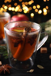 Aromatic hot mulled cider on black wooden table, closeup