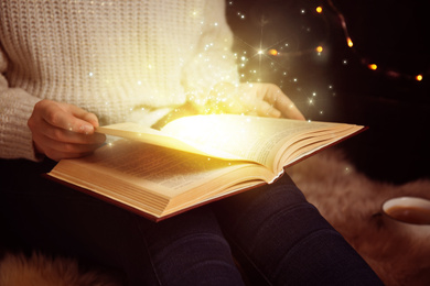 Woman reading shiny magic book, closeup view