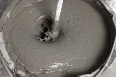 Mixing concrete in bucket indoors, closeup view