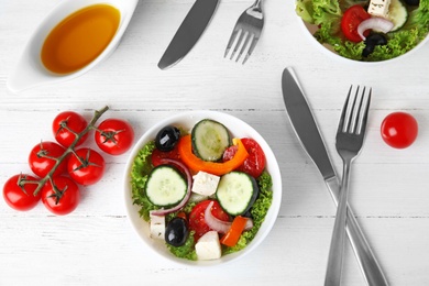 Tasty fresh Greek salad on white wooden table, flat lay