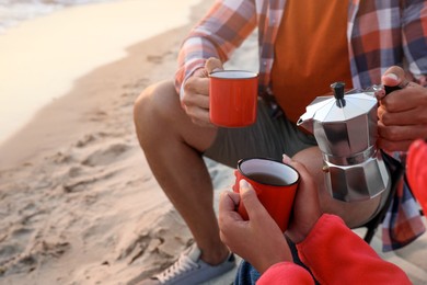 Couple enjoying hot drink on seashore, closeup. Beach camping