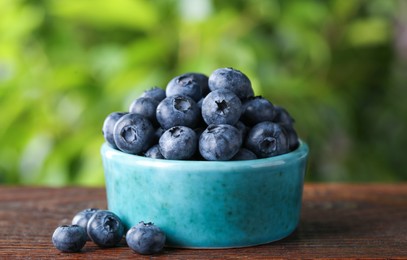 Tasty fresh blueberries on wooden table outdoors, closeup