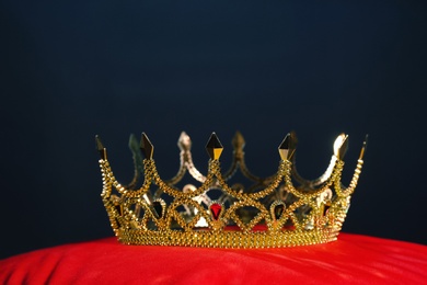Photo of Beautiful golden crown on red velvet pillow. Fantasy item
