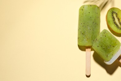 Tasty kiwi ice pops and space for text on pale light beige background, top view. Fruit popsicle