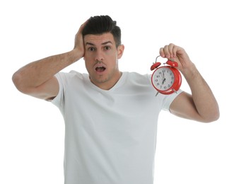 Emotional man with alarm clock on white background. Being late because of oversleeping
