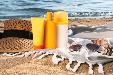 Photo of Sun protection products and beach accessories on blanket near sea