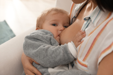 Woman breastfeeding her little baby at home, closeup