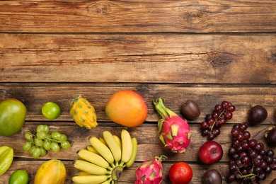 Many different delicious exotic fruits on wooden table, flat lay. Space for text