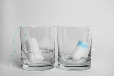 Tampons in glasses on light background. Comparison of absorption