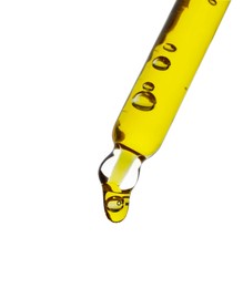 Dripping yellow facial serum from pipette on white background, closeup