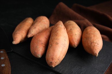 Heap of whole ripe sweet potatoes on black table