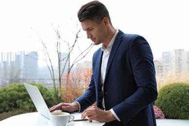 Businessman working with laptop in outdoor cafe. Corporate blog