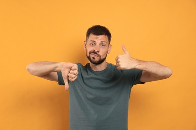 Man showing thumbs up and down on orange background