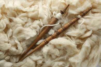 Soft white wool with spindles as background, top view