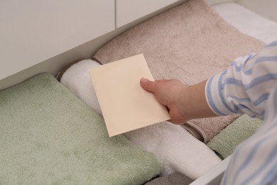 Woman putting scented sachet into drawer with towels, closeup