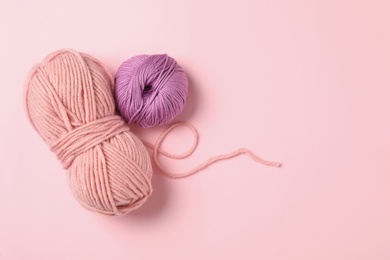 Soft woolen yarns on pink background, flat lay. Space for text