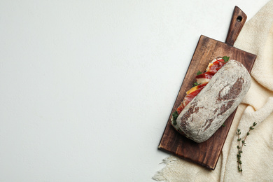 Photo of Delicious sandwich with fresh vegetables and prosciutto on light table, top view. Space for text