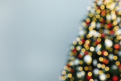 Blurred view of beautifully decorated Christmas tree on grey background, space for text