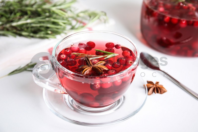 Tasty hot cranberry tea with rosemary and anise on white table