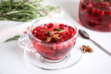 Tasty hot cranberry tea with rosemary and anise on white table