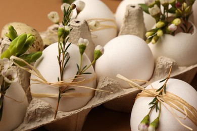 Photo of Festive composition with eggs and floral decor on brown background, closeup. Happy Easter