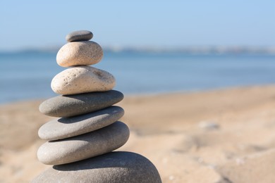 Stack of stones on sandy beach, closeup. Space for text