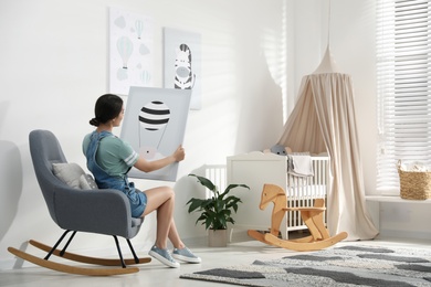 Photo of Decorator with picture sitting indoors. Children's room interior design